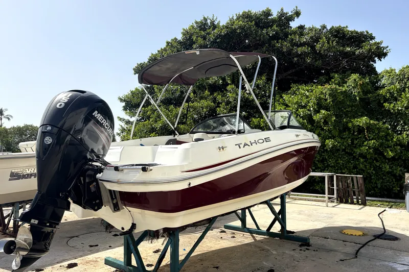 Slide: The Image of 2019 Tahoe 550 TS boat with Mercury outboard motor on a stand, surrounded by greenery. - 7