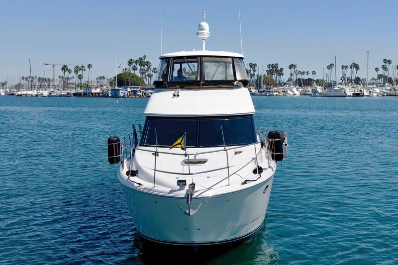 Slide: The Image of A 2014 Meridian 441 Sedan yacht docked in a harbor, surrounded by other boats and palm trees. - 2