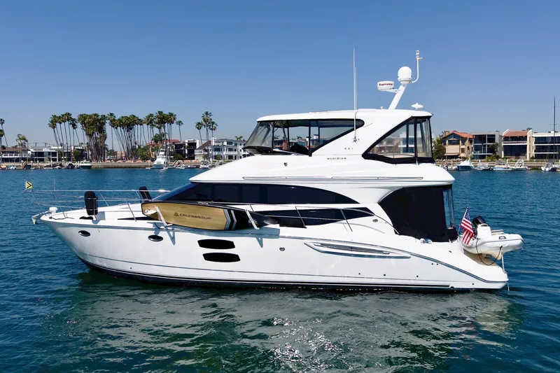 Slide: The Image of A white 2014 Meridian 441 Sedan yacht on calm water, surrounded by coastal houses and palm trees. - 3