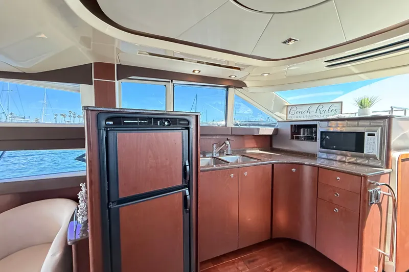 Slide: The Image of The galley of a 2014 Meridian 441 Sedan with wood cabinets, sink, microwave, and refrigerator. - 19