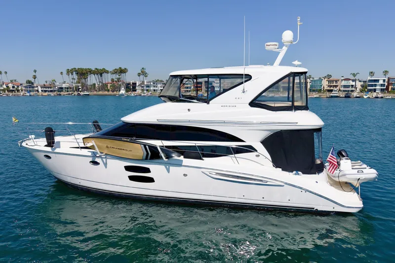 The Image of A white 2014 Meridian 441 Sedan yacht on calm water, featuring modern windows and a dinghy. - 0