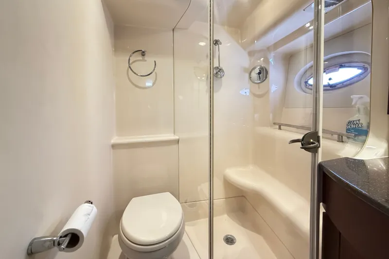 Slide: The Image of The image shows a sleek boat bathroom with a toilet, shower, and porthole. - 27