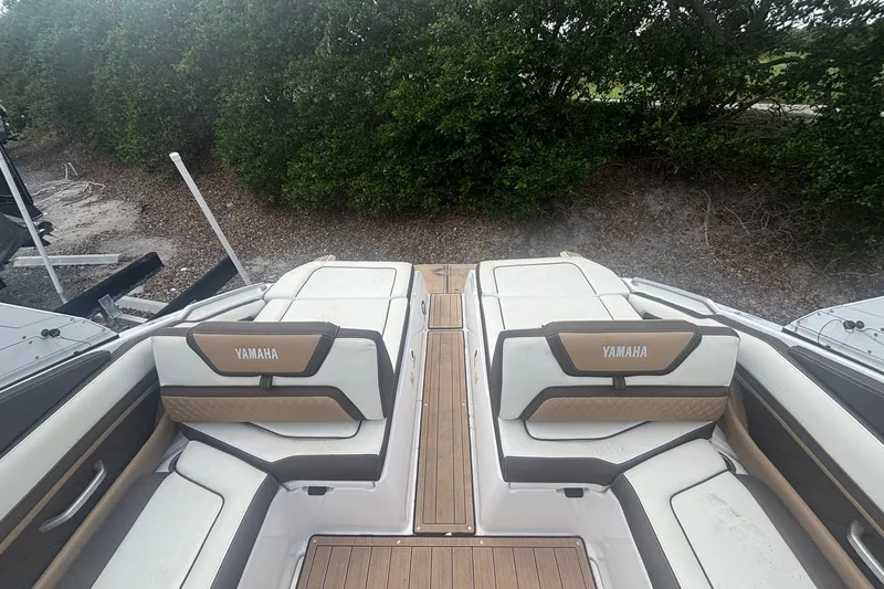 Slide: The Image of 2021 Yamaha Boats 275SE interior with cushioned seating and wood accents, surrounded by greenery. - 10