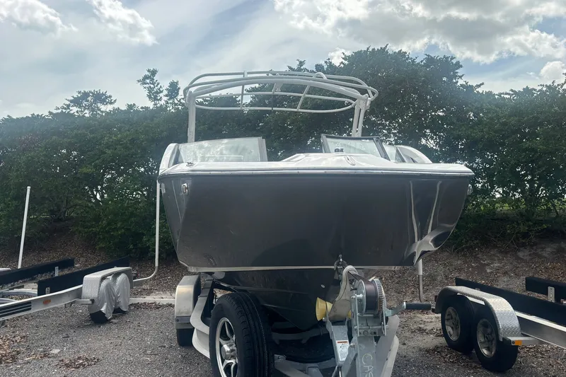 Slide: The Image of 2021 Yamaha Boats 275SE on trailer, parked outdoors under cloudy sky. - 2