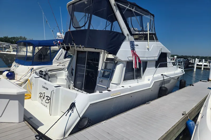 The Image of 1998 Carver 370 Voyager yacht docked at marina under clear blue sky. - 1