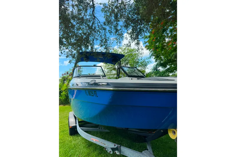 Slide: The Image of 2015 Yamaha Boats AR240 in blue, parked on a trailer under trees. - 5
