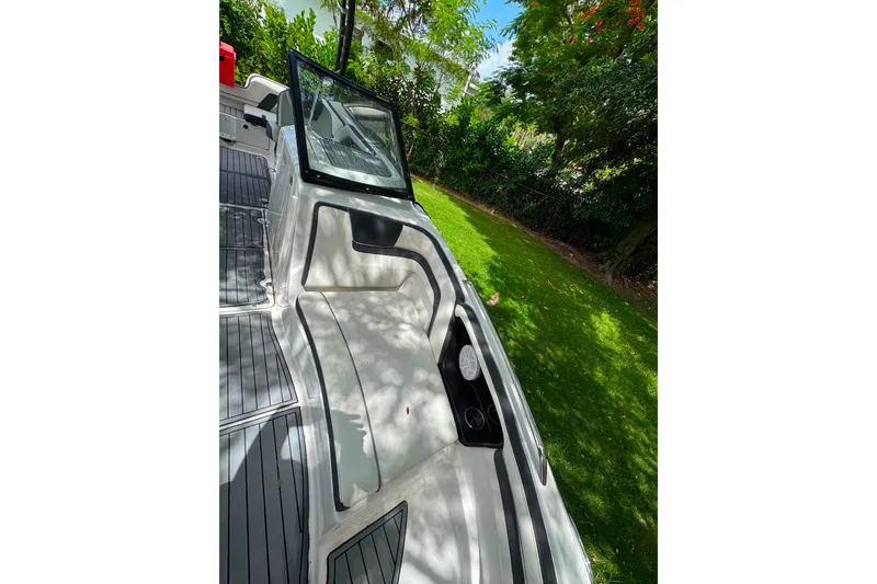 Slide: The Image of 2015 Yamaha Boats AR240 interior with seating and cup holders, surrounded by lush greenery. - 20
