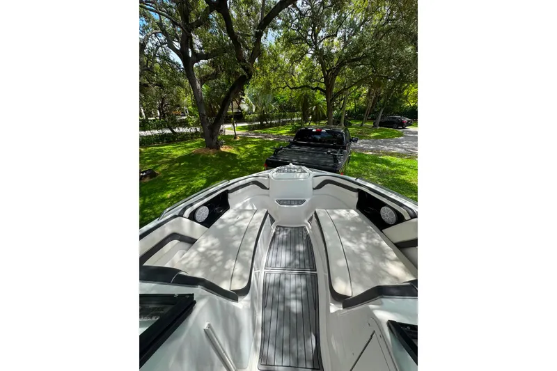 Slide: The Image of 2015 Yamaha AR240 boat interior with seating, parked under trees. - 19