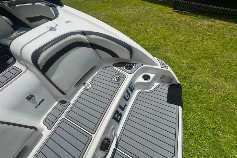 Slide: The Image of 2015 Yamaha Boats AR240 interior with cushioned seating and cup holders on grass. - 21