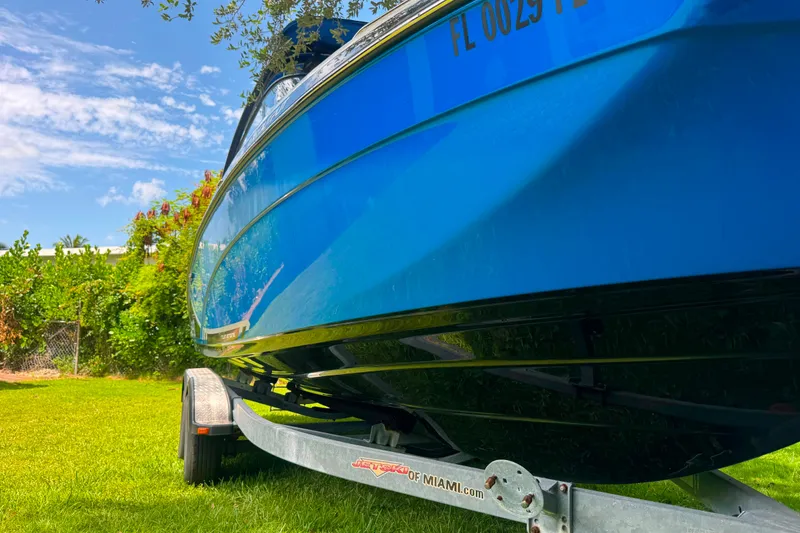 Slide: The Image of 2015 Yamaha Boats AR240 on trailer, vibrant blue hull, parked on grass under clear sky. - 3
