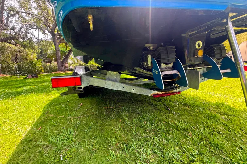 Slide: The Image of 2015 Yamaha Boats AR240 on trailer, showing propellers and hull, parked on grass. - 47