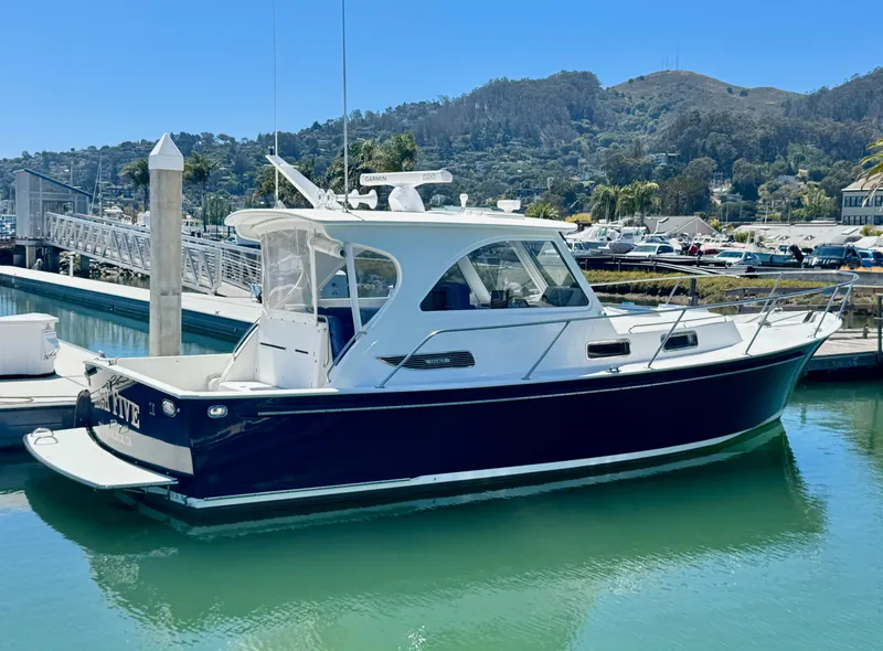 Slide: The Image of A 2003 Legacy 34 Express boat docked in a calm harbor setting. - 1
