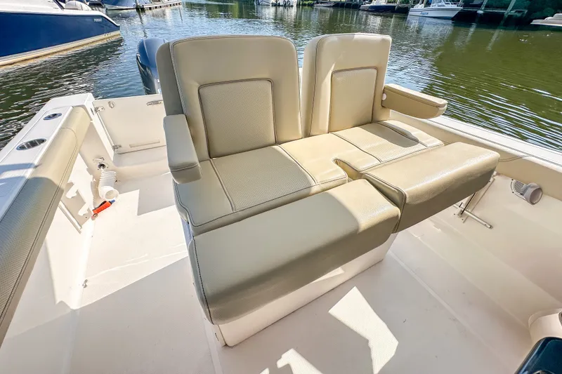 Slide: The Image of 2018 Pursuit C 260 Center Console boat with beige seating, docked on calm water. - 31