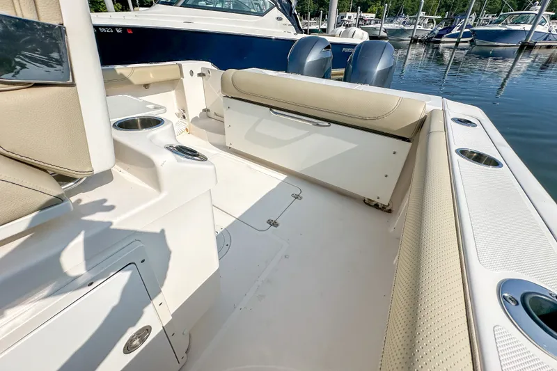 Slide: The Image of 2018 Pursuit C 260 Center Console boat interior with seating and cup holders at marina. - 43