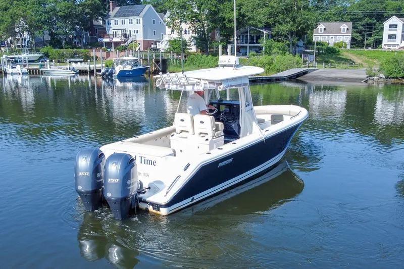 Slide: The Image of 2018 Pursuit C 260 Center Console boat on calm water near a residential shoreline. - 10