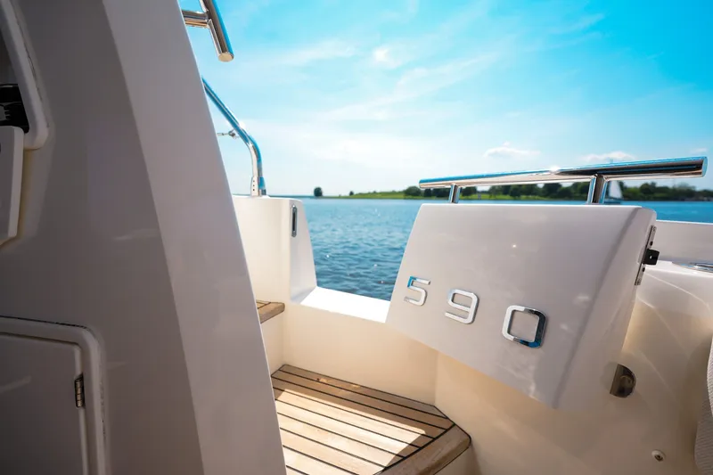 Slide: The Image of Luxury 2023 Prestige 590 yacht with sleek design, overlooking serene water and blue sky. - 25