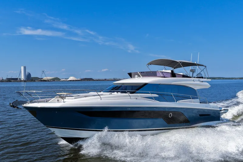 Slide: The Image of 2023 Prestige 590 yacht cruising on open water under a clear blue sky. - 13