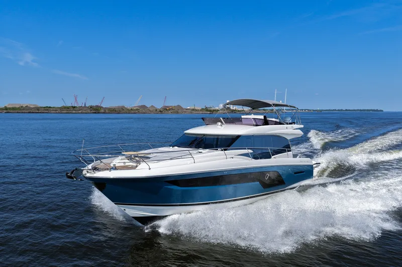 Slide: The Image of 2023 Prestige 590 yacht cruising on open water under clear blue skies. - 18