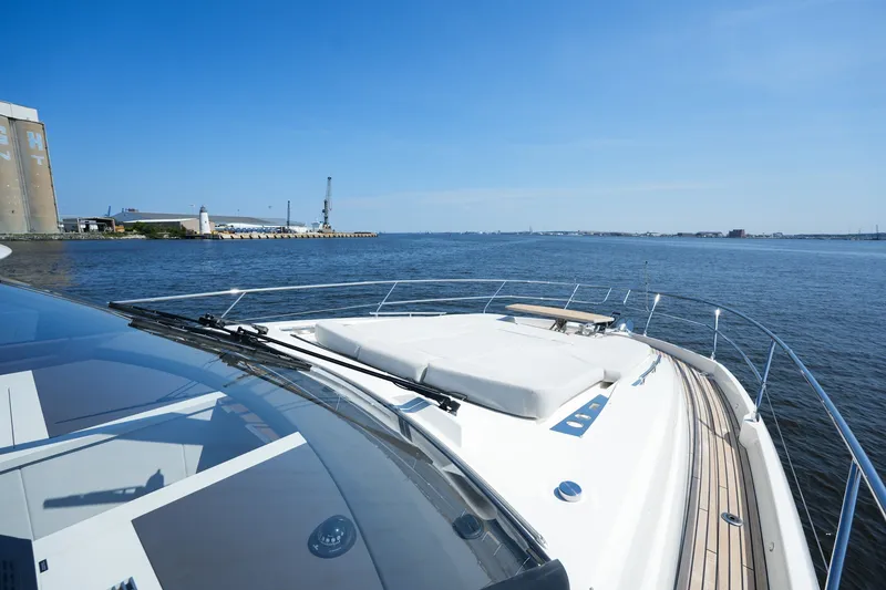Slide: The Image of 2023 Prestige 590 yacht cruising on a sunny day near an industrial waterfront. - 46