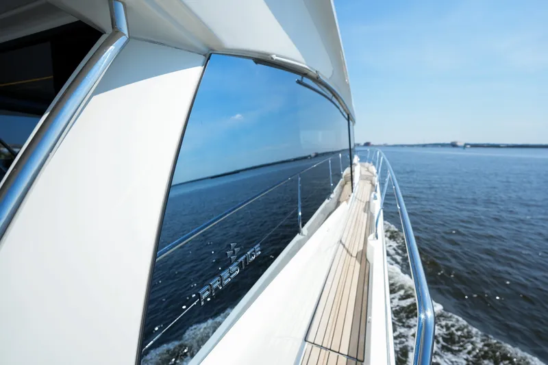 Slide: The Image of 2023 Prestige 590 yacht cruising on open water under clear blue skies. - 45