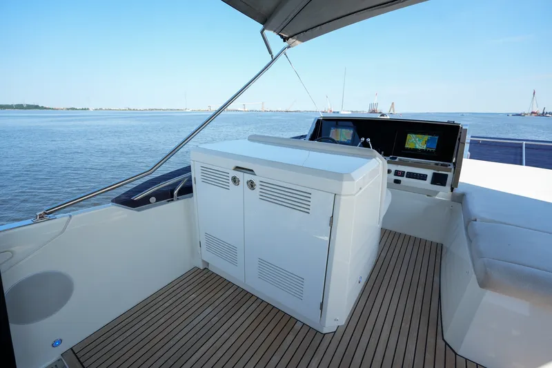 Slide: The Image of Flybridge of 2023 Prestige 590 yacht with navigation screens, overlooking calm waters. - 41