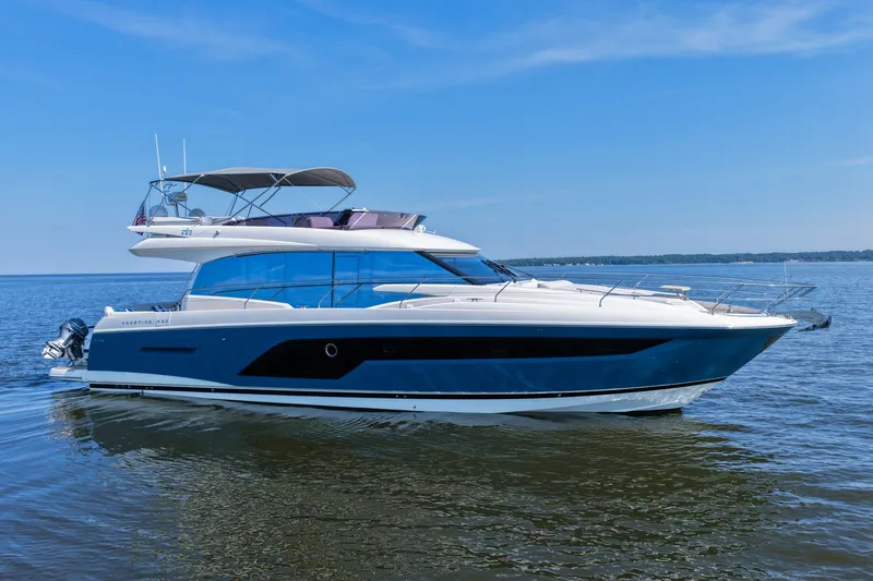 Slide: The Image of 2023 Prestige 590 yacht cruising on calm waters under a clear blue sky. - 7