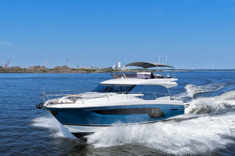 Slide: The Image of 2023 Prestige 590 yacht cruising on open water under clear blue sky. - 17