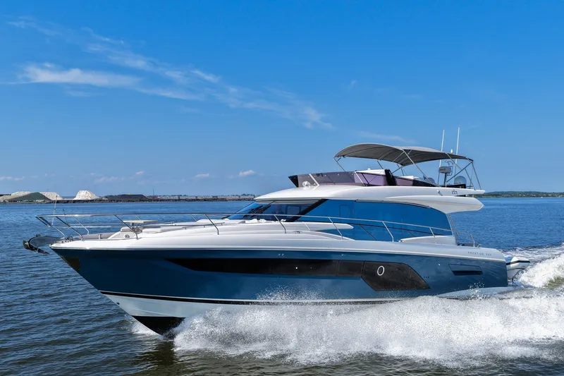 Slide: The Image of Luxury 2023 Prestige 590 yacht cruising on open water under clear blue sky. - 11