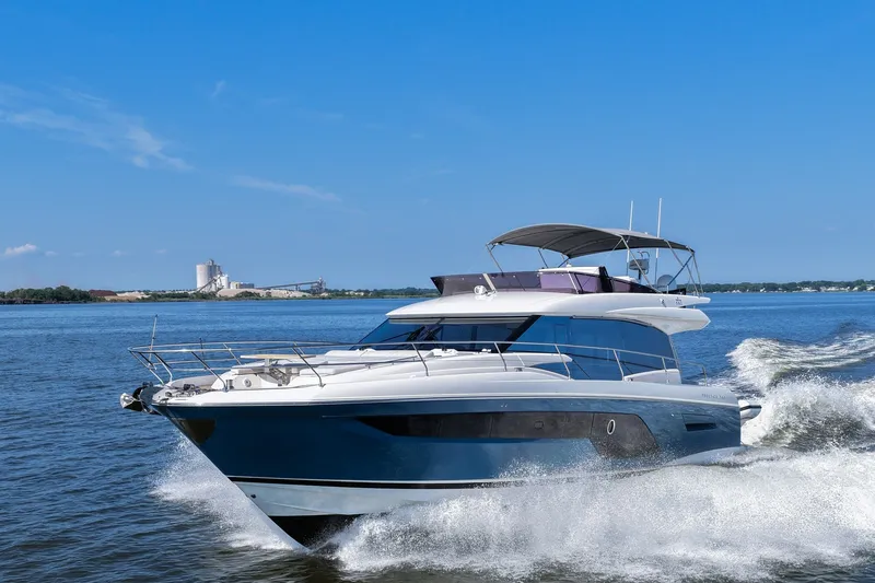 Slide: The Image of 2023 Prestige 590 yacht cruising on a sunny day, creating waves in open water. - 12