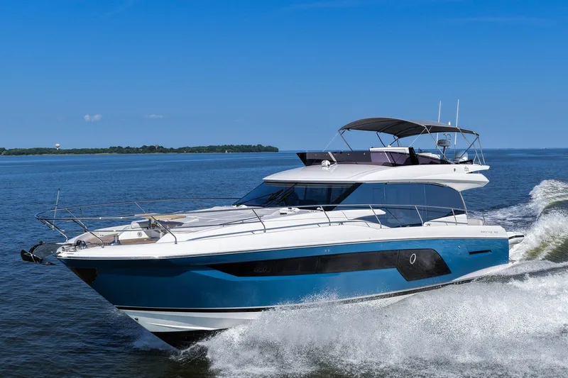 The Image of Luxury 2023 Prestige 590 yacht cruising on open water under clear blue sky. - 0