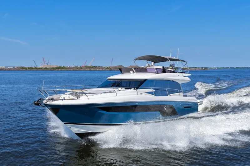 Slide: The Image of 2023 Prestige 590 yacht cruising on open water under clear blue skies. - 15