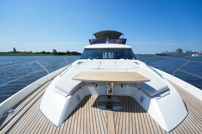 Slide: The Image of 2023 Prestige 590 yacht deck with seating and table on calm water. - 48