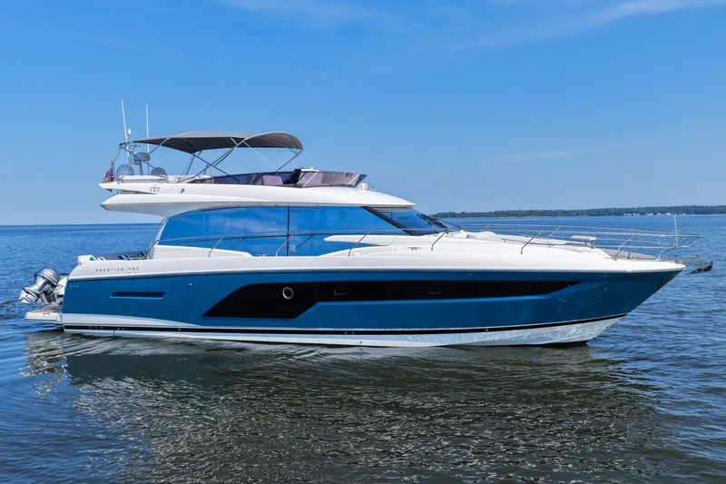 Slide: The Image of 2023 Prestige 590 yacht cruising on calm waters under a clear blue sky. - 6