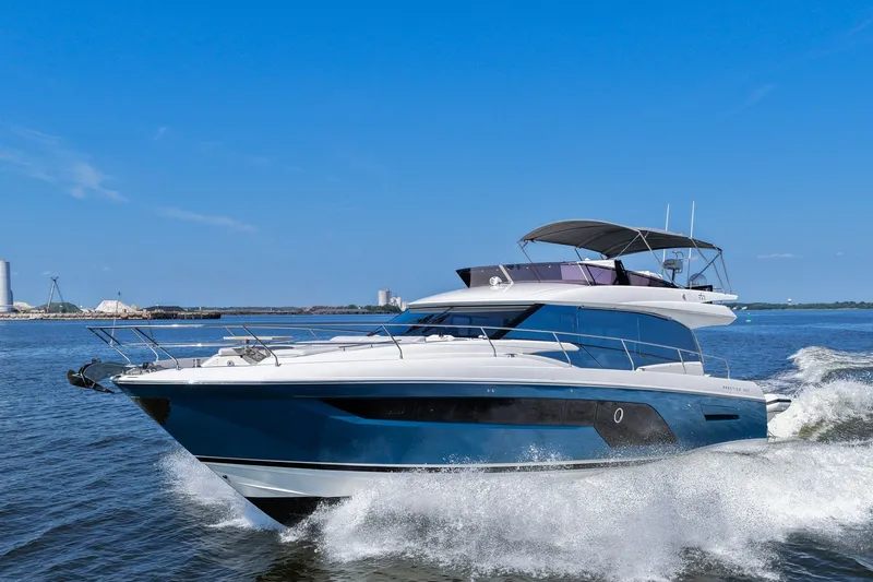 Slide: The Image of 2023 Prestige 590 yacht cruising on open water under a clear blue sky. - 14