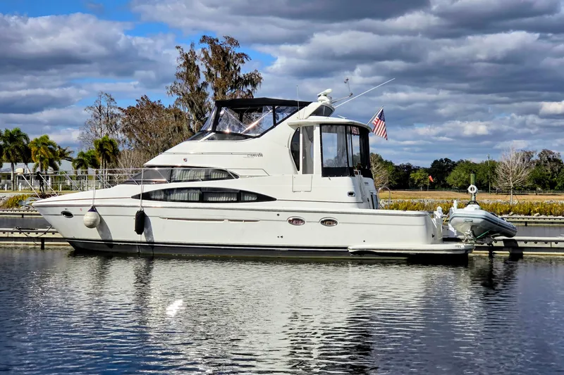 The Image of 2005 Carver 444 Cockpit Motor Yacht docked on a calm, scenic waterway. - 0