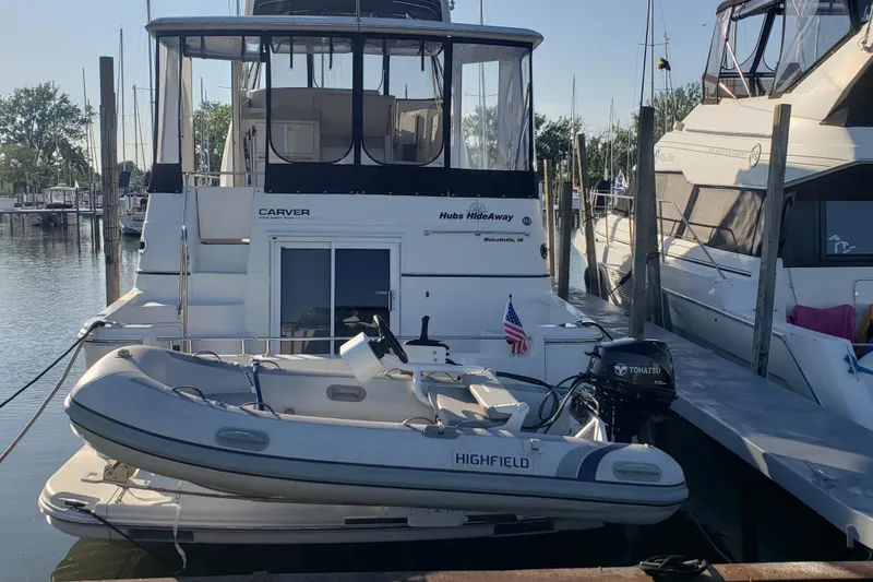 Slide: The Image of 2005 Carver 444 Cockpit Motor Yacht docked with inflatable boat, marina background. - 2
