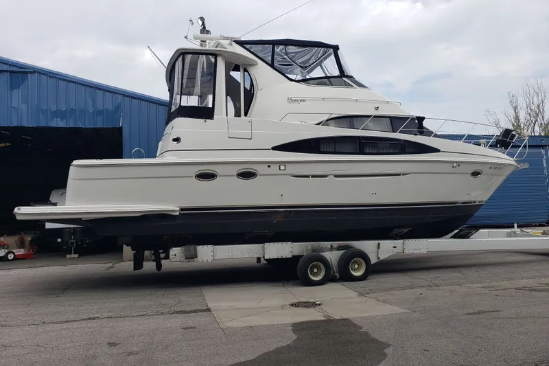 Slide: The Image of A 2005 Carver 444 Cockpit Motor Yacht on a trailer in front of a blue building. - 1