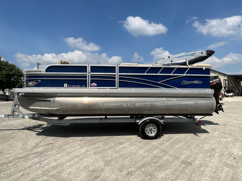 The Image of A 2016 SilverWave 210L pontoon boat on a trailer. It features a blue and silver exterior. - 1