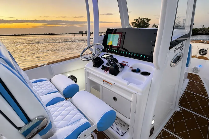 Slide: The Image of 2018 Sea Hunt Gamefish 27 Coffin Box boat interior at sunset, featuring helm and seating. - 33