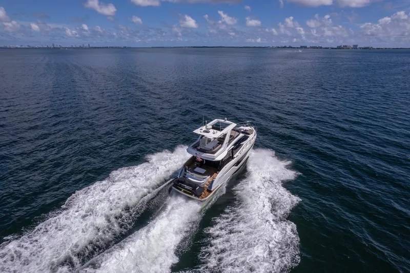 Slide: The Image of A 2021 Galeon 500 Fly yacht cruising on open water under a clear blue sky. - 3