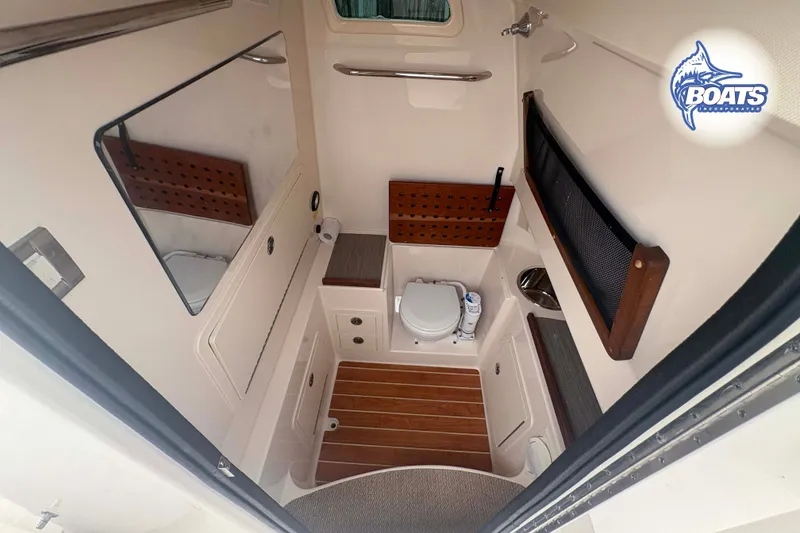 Slide: The Image of 2024 Grady-White Canyon 306 boat interior with compact bathroom and wooden accents. - 9
