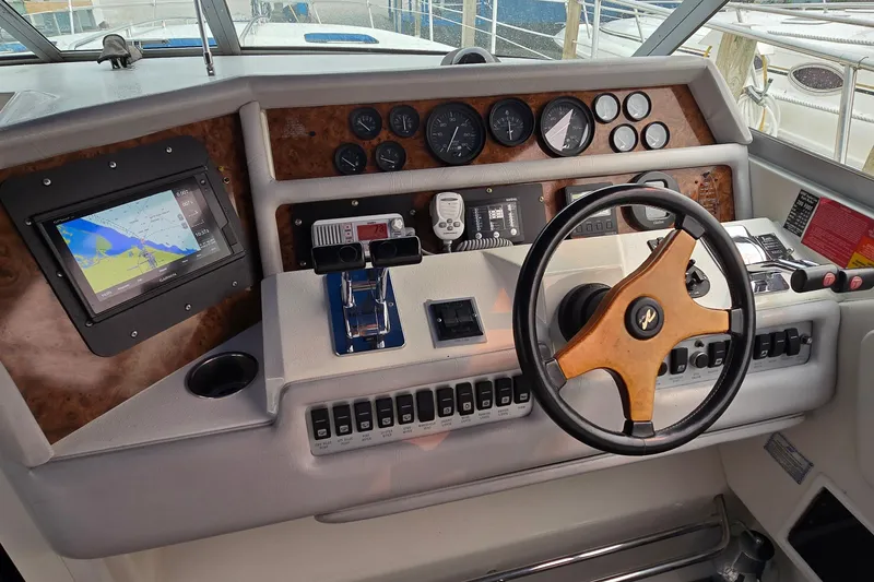 Slide: The Image of 1994 Sea Ray 370 Express Cruiser helm with navigation system and classic wooden steering wheel. - 16