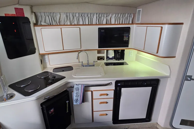 Slide: The Image of 1994 Sea Ray 370 Express Cruiser kitchen with stove, sink, microwave, and compact fridge. - 23