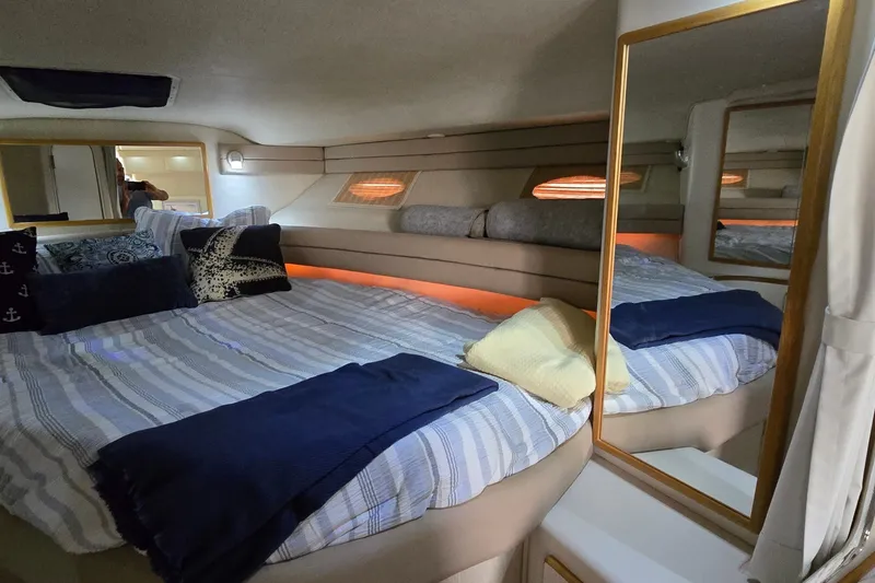 Slide: The Image of Cozy cabin interior of 1994 Sea Ray 370 Express Cruiser with comfortable bedding and ambient lighting. - 26