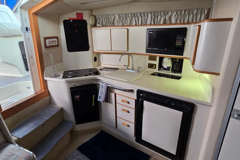 Slide: The Image of 1994 Sea Ray 370 Express Cruiser kitchen with stove, sink, microwave, and refrigerator. - 22