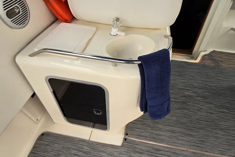 Slide: The Image of 1994 Sea Ray 370 Express Cruiser sink area with blue towel and storage cabinet. - 12