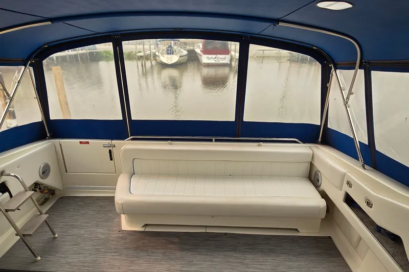 Slide: The Image of 1994 Sea Ray 370 Express Cruiser interior with white seating and blue canopy, docked at marina. - 11