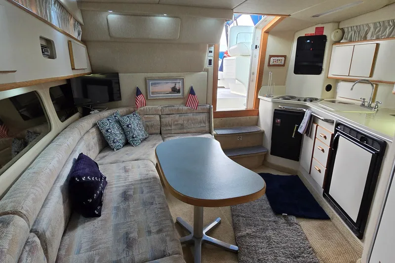 Slide: The Image of Interior of a 1994 Sea Ray 370 Express Cruiser with cozy seating and compact kitchen. - 30