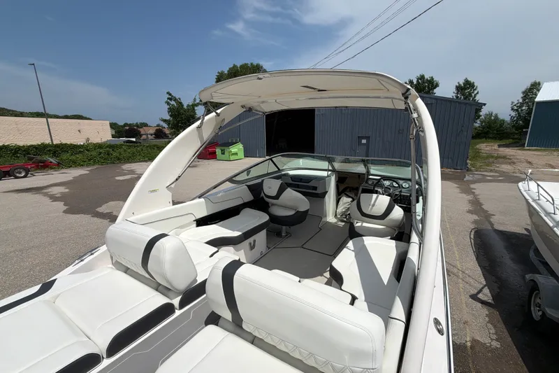 Slide: The Image of 2020 Regal 2300 Bowrider boat with white interior, parked outdoors near industrial buildings. - 7