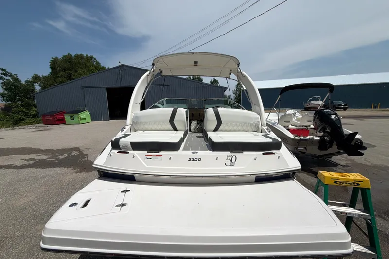 Slide: The Image of 2020 Regal 2300 Bowrider boat with white seating, parked outdoors near a warehouse. - 6